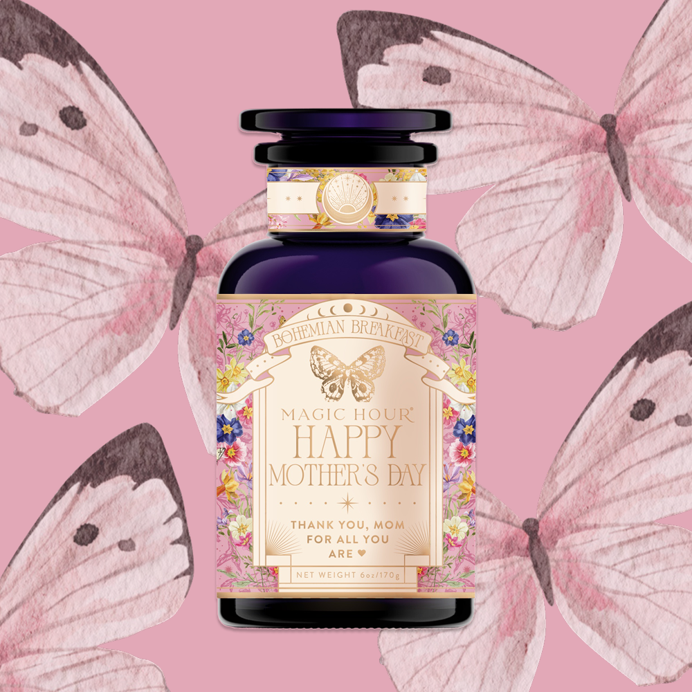 A decorative tea jar labeled "Bohemian Breakfast Limited Edition Mother's Day" with floral designs and butterflies, thanking mom, featuring vanilla puerh black tea for digestion & energy, set against a pink background.