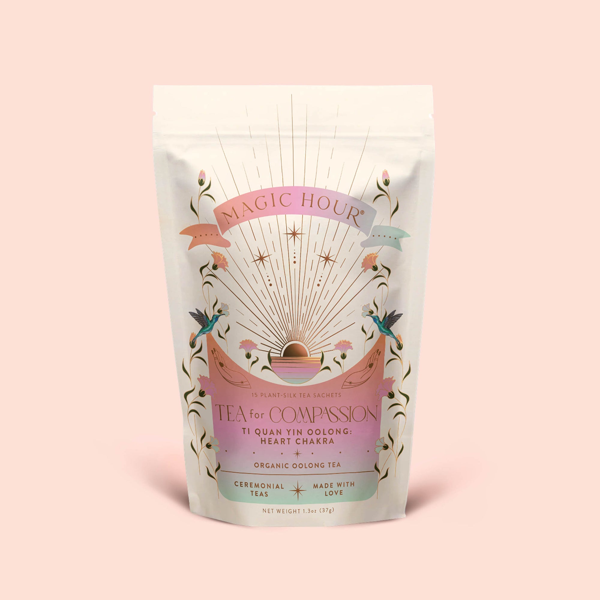 A pastel-colored pouch labeled "Tea for Compassion: Ti Quan Yin: Organic Oolong Tea" features celestial and floral designs, with text highlighting its blend as an oolong tea crafted to support the heart chakra. The package contains original style organic Ti Quan Yin oolong made through long fermentation, and is shown resting against a pale pink background.