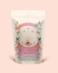 A pastel-colored pouch labeled "Tea for Compassion: Ti Quan Yin: Organic Oolong Tea" features celestial and floral designs, with text highlighting its blend as an oolong tea crafted to support the heart chakra. The package contains original style organic Ti Quan Yin oolong made through long fermentation, and is shown resting against a pale pink background.