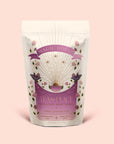 A pastel pink tea package labeled "Tea for Peace: Child's Pose" features floral illustrations, gold rays, and decorative text that highlights its citrus, lavender, and tulsi herbal tea blend. The packaging’s gentle, soothing design invites you to relax your nervous system with each sip.