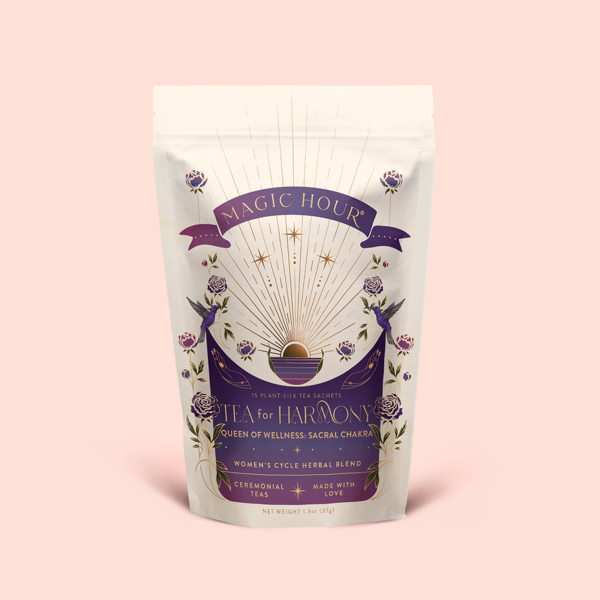 A white and purple Magic Hour tea pouch labeled "Tea for Harmony: Queen of Wellness: Women's Cycle Herbal Blend," featuring floral and celestial designs, with text highlighting it's a women's herbal tea blend with organic chaste berry and raspberry leaf, specially crafted to support the sacral chakra.