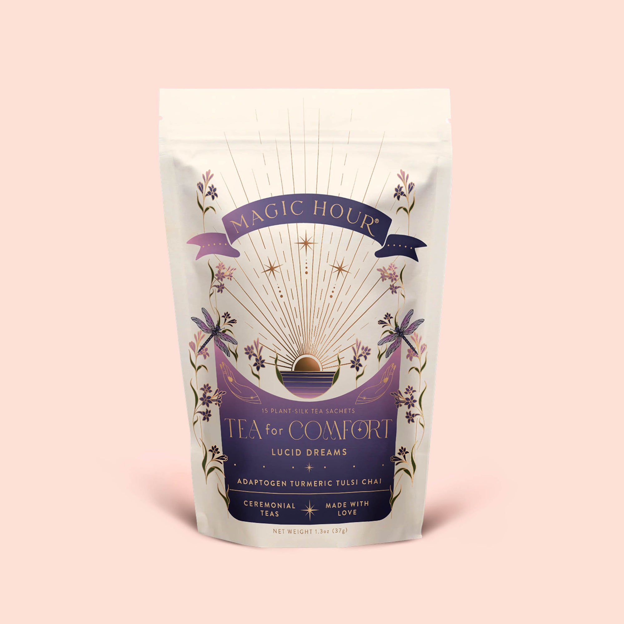 A pastel pouch labeled “Tea for Comfort: Lucid Dreams: Turmeric-Tulsi Chai Tea” features celestial and floral artwork, highlighting a soothing, caffeine-free blend of Tulsi and turmeric. This ceremonial herbal tea for sleep is “made with love” and sits gracefully on a soft pink background.