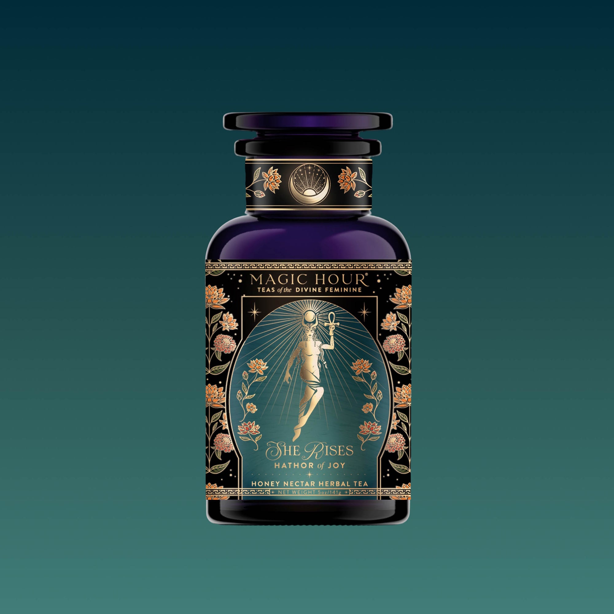 A dark glass bottle from the Monthly Magic Tea Journey Subscription, adorned with gold floral details and a radiant goddess on the label, evokes goddess ritual and herbal wellness against a teal background.