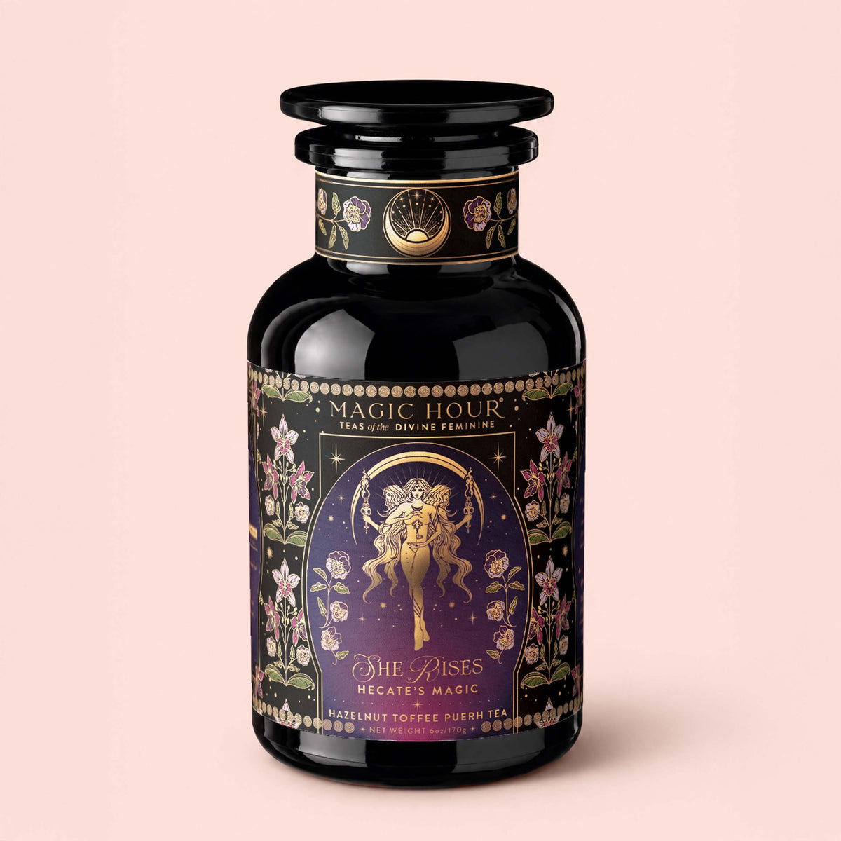 A black tea jar labeled “Monthly Magic Tea Journey Subscription” with floral designs, celestial motifs, and two figures sits against a light pink background.