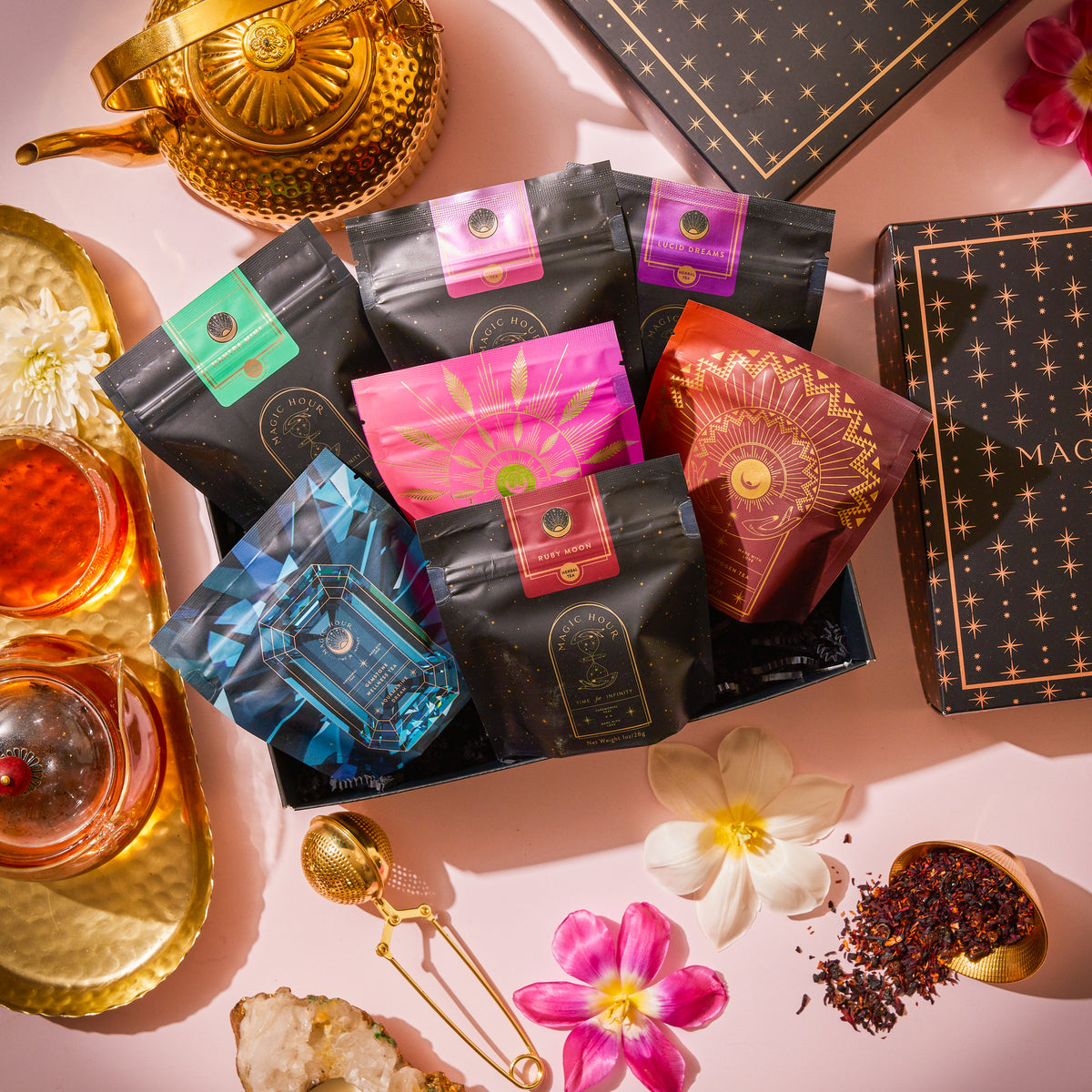 Herbal Tea Sampler Tea Box: Caffeine-Free Teas for Sleep, Digestion & Immunity featuring seven colorful herbal tea pouches, surrounded by a gold teapot, two cups of brewed tea, flowers, and a tea infuser.