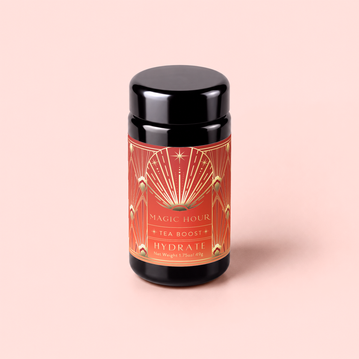 A black tea canister with a red and gold label reading “Hydrate Tea Boost” sits on a light pink background. The label, inspired by the vibrant energy of a botanical elixir, features geometric designs and a starburst motif.