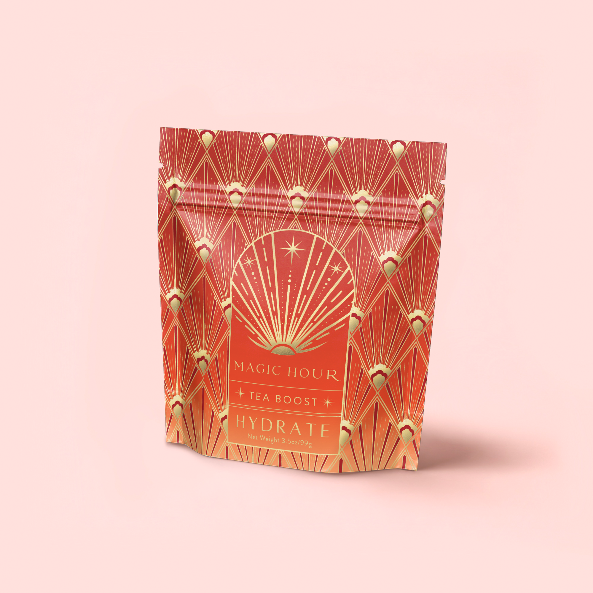 A red and gold resealable pouch labeled "Hydrate Tea Boost" with an art deco pattern and starburst design stands upright on a light pink background, emphasizing its hydration benefits from nutrient-rich botanicals.