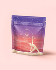 A stand-up pouch of "Kapha: Caffeine-Free Saffron Spice Tea" features a gradient purple-red design, starry background, and a woman’s yoga pose silhouette. This ayurvedic tea supports Kapha balance and promotes digestion for inner wellness.
