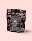 A black and gold floral package labeled "Goddess of Earl: Lady Luck Oriental Beauty Oolong Tea" stands against a light pink background. The label highlights its organic loose leaf Oolong with bergamot essence, made with love.