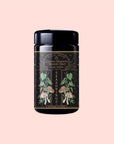 A black jar labeled "Lapsang Souchong," adorned with botanical art and "Seasonings" in gold, sits on a pale pink background—this blend features smoky black tea seasoning paired with earthy mushroom powder.