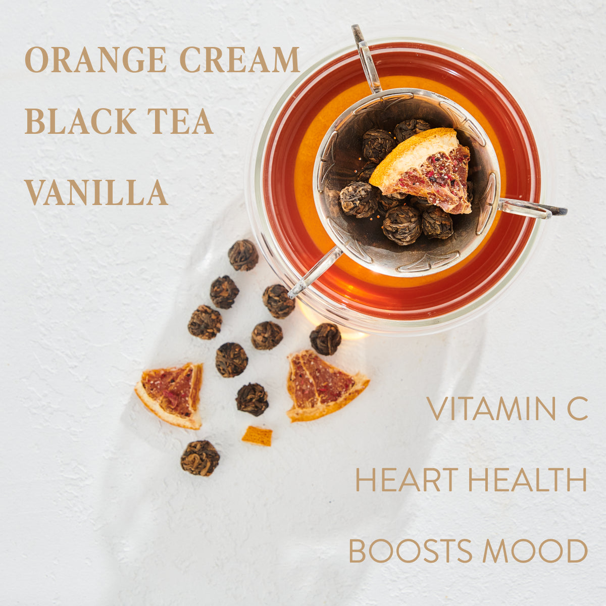 A glass of tea with an infuser containing a dried orange slice and tea balls. Surrounding the glass are additional tea balls and orange slices. Text on image reads: "ORANGE CREAM, BLACK TEA, VANILLA" and "VITAMIN C, HEART HEALTH, BOOSTS MOOD." Experience the magic of Leo: Queen of Courage Tea of the Sun by Magic Hour.