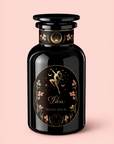 A black glass bottle with a gold and pink label adorned with zodiac Libra imagery, delicate floral details, and the words “Libra Shatavari-Cardamom-Rose White Love Cake Tea,” displayed on a pale pink background—an enchanting vessel inspired by Persian love cake tea, evoking subtle notes of rose pistachio tea.