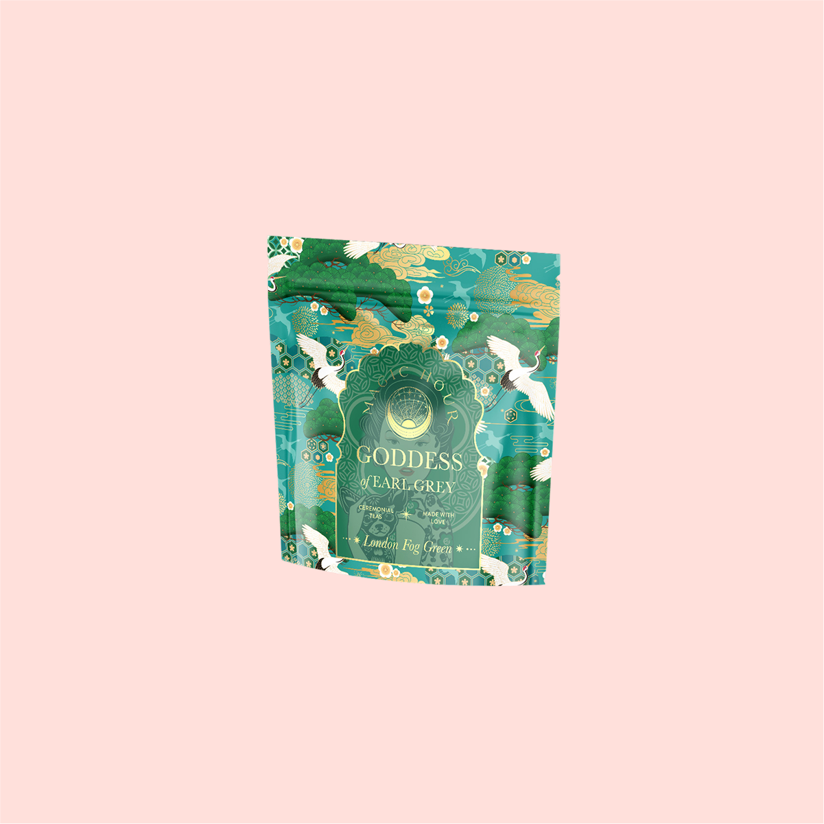 A teal and gold ornate bag of London Fog Green tea, infused with bergamot, is centered on a light pink background. The package boasts intricate patterns and an elegant design.