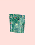 A decorative teal packaging of "London Fog Oolong" tea with ornate floral and leaf patterns, featuring a gold-lettered label against a light pink backdrop, hinting at the rich bergamot aroma within.