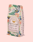 A decorative tea package featuring floral and peacock patterns, labeled "Magic Hour Goddess of Earl Grey," contains ceremonial tea with bergamot. The product is named London Fog White, set against a pale pink background.