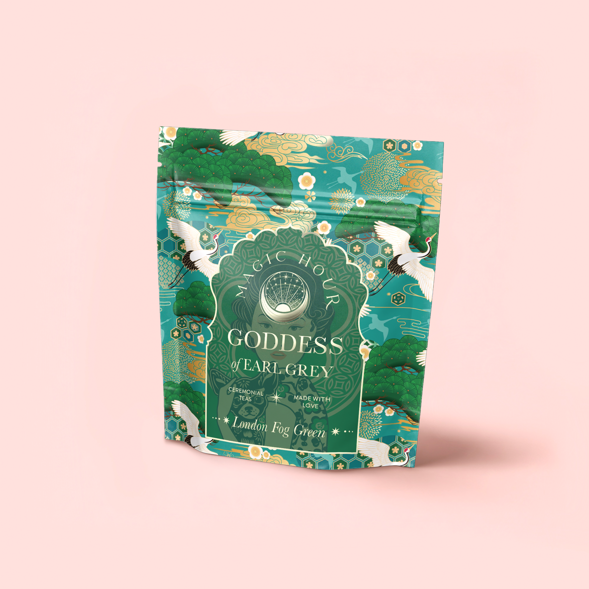 A vibrant tea package labeled “London Fog Green” stands upright on a pale pink background, adorned with green nature motifs and white cranes. The packaging highlights bergamot and lavender notes, and also features "Goddess of Earl Grey.