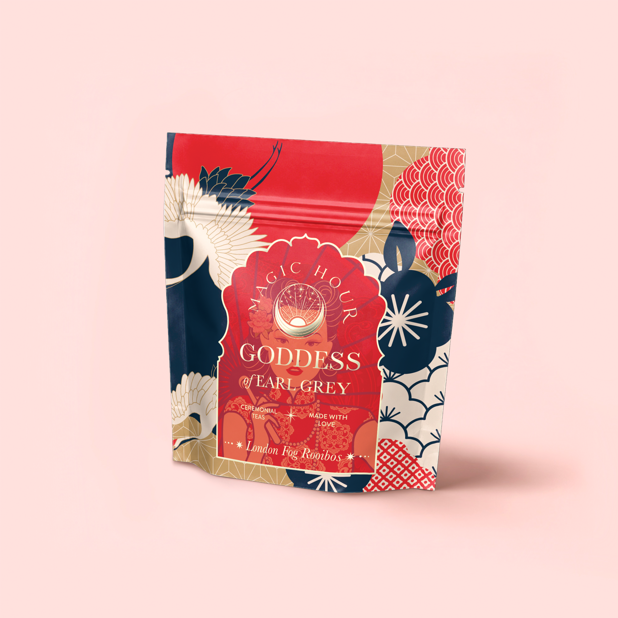 A colorful pouch of Magic Hour London Fog Rooibos tea with bold red, gold, blue, and cream floral patterns stands on a light pink surface—featuring hints of bergamot for a vibrant twist. The brand and tea name are displayed on the front.