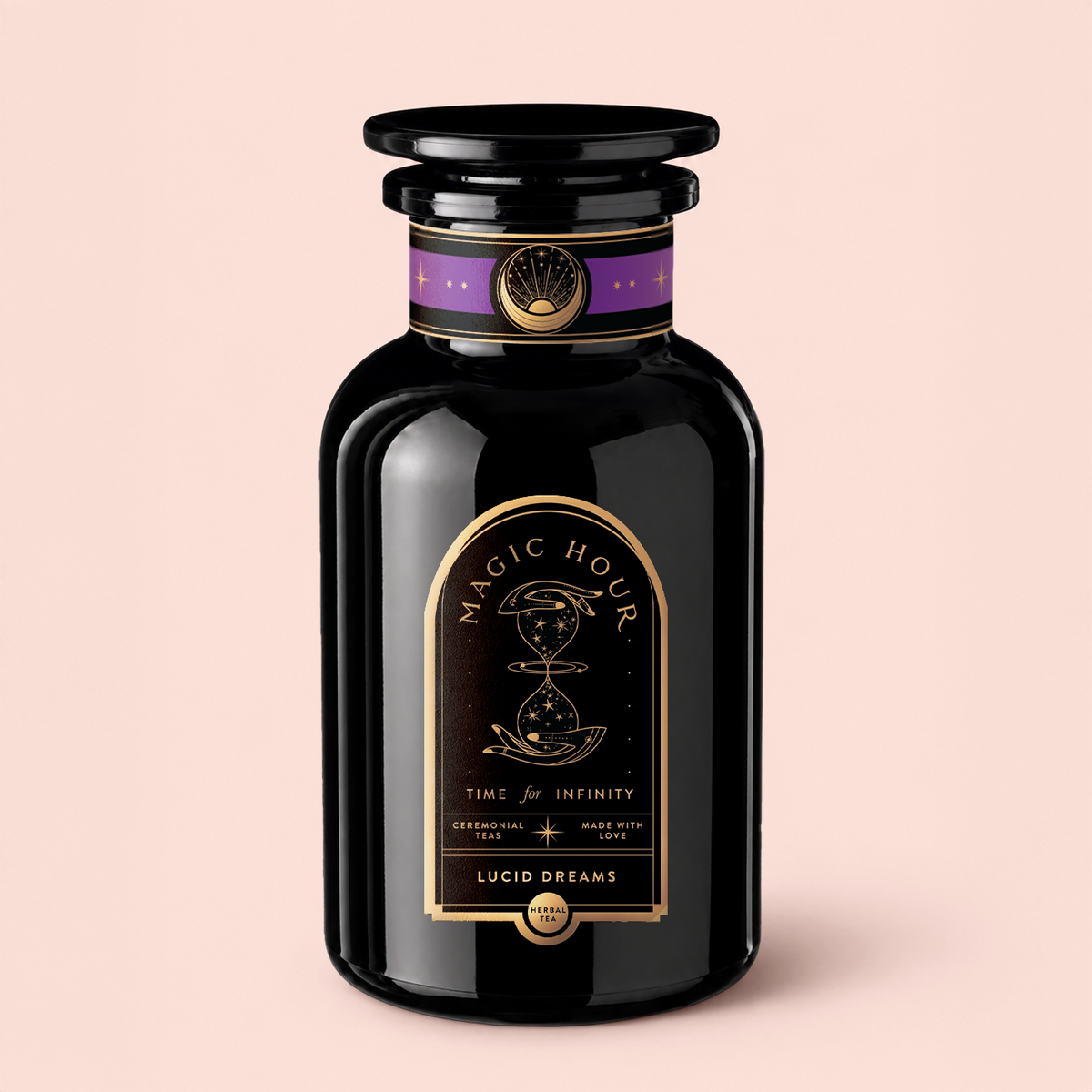 A glossy black jar labeled “Magic Hour Lucid Dreams: Tulsi-Turmeric Herbal Tea for Sleep &amp; Calm” sits on a pale pink background. The label, adorned with gold and purple celestial designs and the phrase “Time for Infinity,” hints at the enchanting blend within—a soothing, caffeine-free chai crafted to inspire relaxation and wonder.