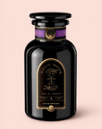 A glossy black jar labeled “Magic Hour Lucid Dreams: Tulsi-Turmeric Herbal Tea for Sleep & Calm” sits on a pale pink background. The label, adorned with gold and purple celestial designs and the phrase “Time for Infinity,” hints at the enchanting blend within—a soothing, caffeine-free chai crafted to inspire relaxation and wonder.