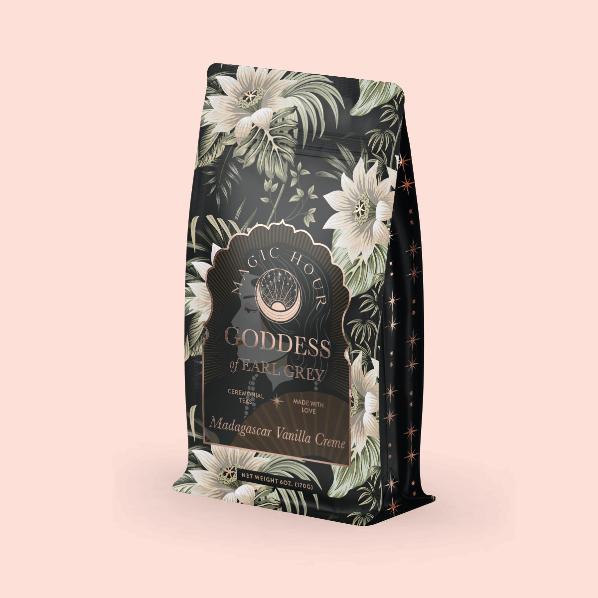 A decorative tea package features a soft pink floral design with the label "Madagascar Vanilla Earl Grey Creme Tea," highlighting notes of Madagascar Vanilla Creme and organic black tea, complemented by intricate patterns and vanilla orchid hints.