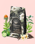 A floral Magic Hour tea package labeled “Madagascar Vanilla Earl Grey Creme Tea Refill Pouch” is surrounded by bergamot, vanilla, white flowers, green leaves, and dark tea leaves on a light pink background—an enticing display that hints at the rich aroma of organic black tea complemented by delicate golden-tipped notes.