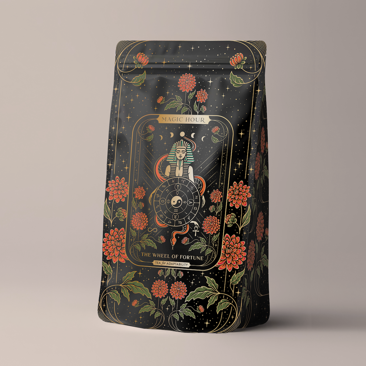 A black coffee bag intricately designed with gold and red floral patterns. At its center is an illustration of a mystical figure holding a wheel, alongside the text &quot;Magic Hour&quot; and &quot;The Wheel of Fortune.&quot; The background showcases an array of stars and celestial motifs.