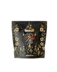 A decorative tea package featuring floral patterns and stars, adorned with a colorful abstract design of a steaming cup. It has the label "Magic Hour" alongside "The World," set against a black background with intricate gold details.