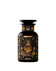 A dark amber bottle from Magic Hour, adorned with ornate label designs, features an illustration of a woman in a yellow dress surrounded by sunflowers and foliage. Titled "The Sun: Energizing Adaptogenic Herbal Tea with Yaupon, Moringa & Turmeric," the bottle has a black cap and displays intricate floral patterns with a mystical theme.