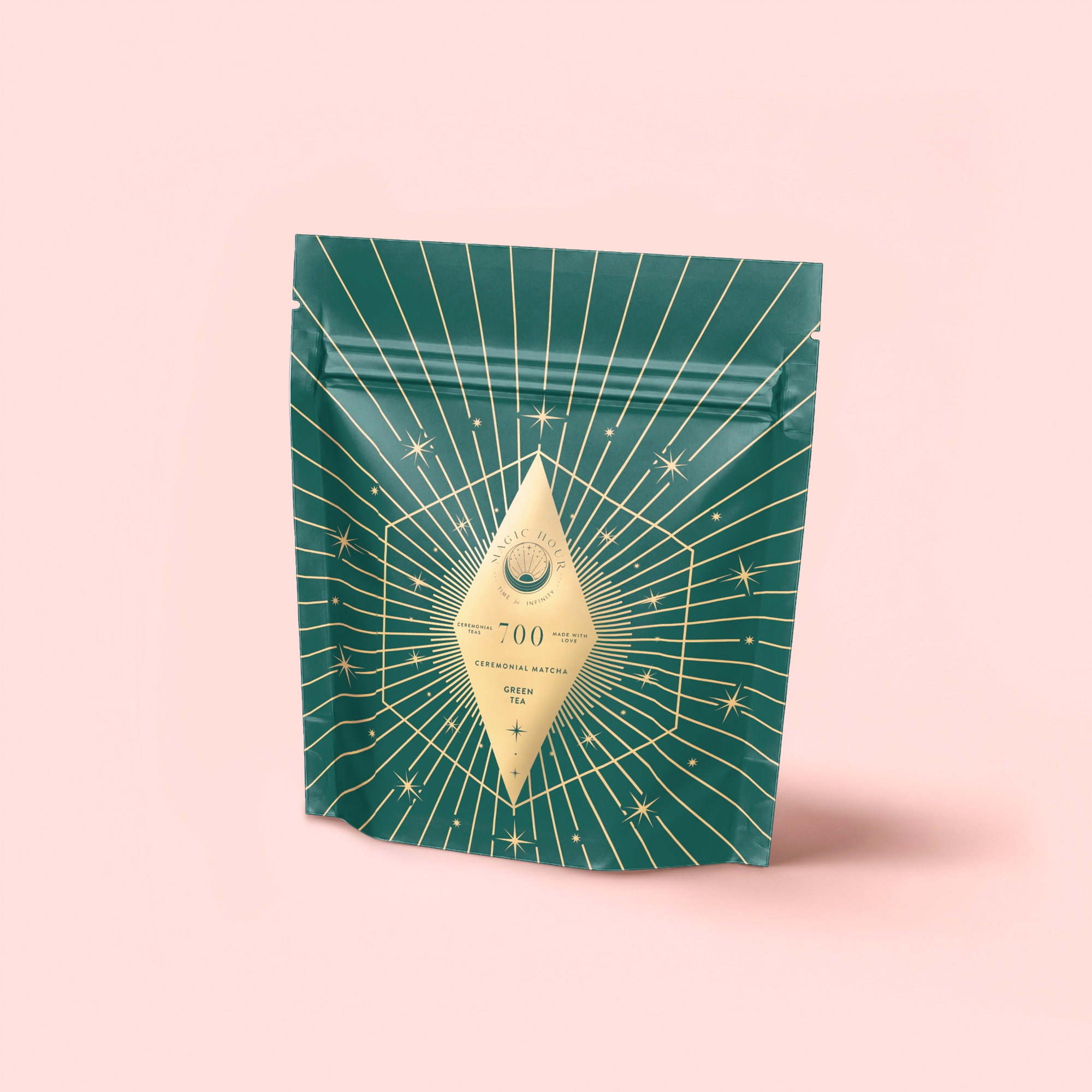 A green resealable pouch with gold starburst and line designs displays a diamond label reading "700" and "Green" on pale pink—ideal for presenting Organic Ceremonial Matcha 700 from Kagoshima.