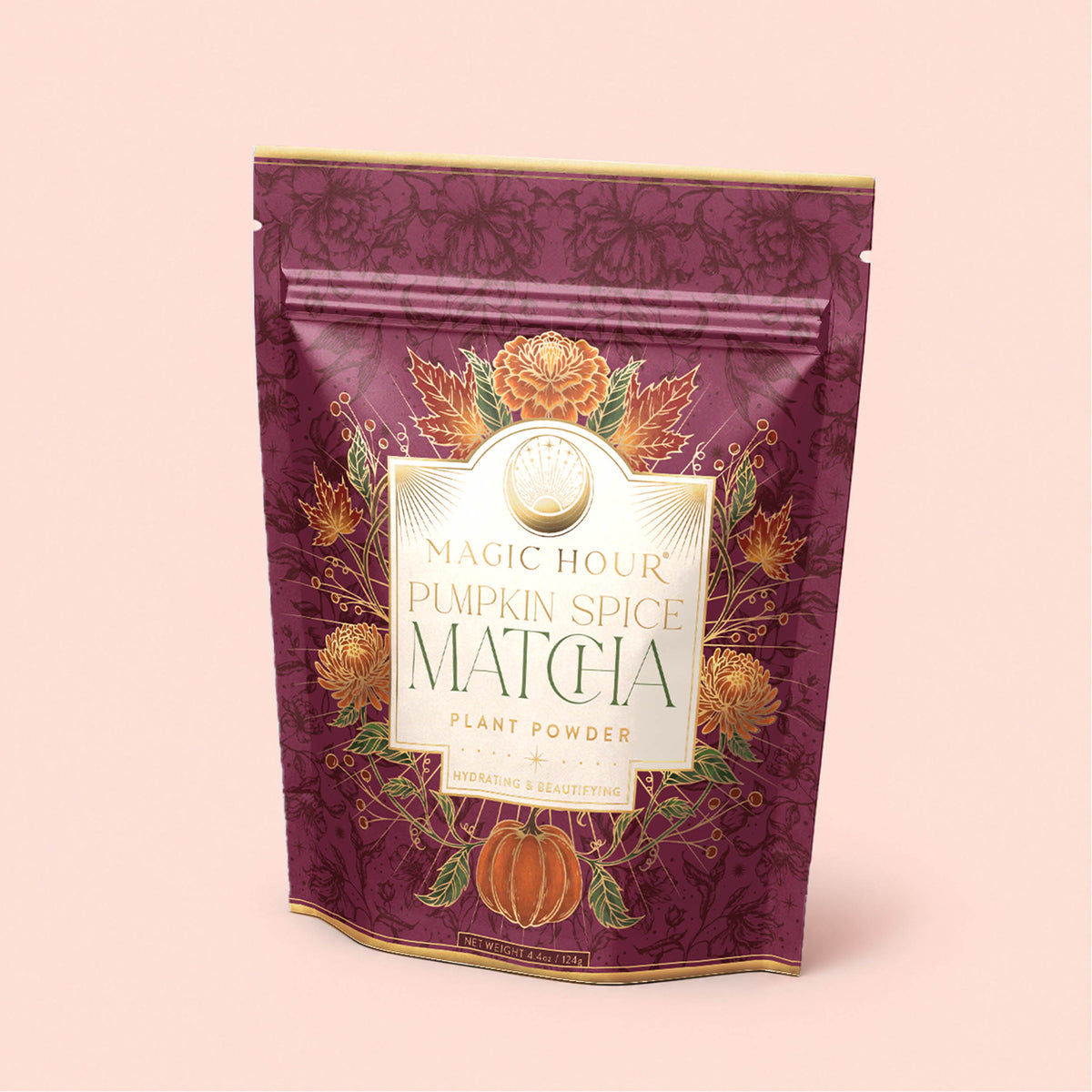 A purple resealable pouch labeled “Pumpkin Spice Matcha,” adorned with gold accents, orange flowers, and a pumpkin illustration on the front, set against a light pink background—this elegant packaging highlights autumn botanicals and features the rich flavor of ceremonial matcha expertly blended with warming pumpkin spice.