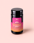 A black jar with a vibrant pink and orange label reading “Mercury Mint Daytime” on a light pink background. The label features decorative designs and mystical symbols, hinting at the soothing blend of vanilla mint, lavender, jasmine, and biodynamic black tea infused within.