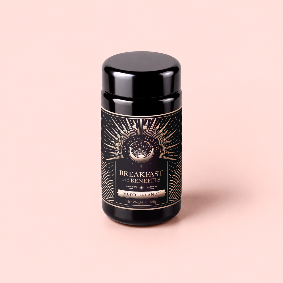 A black jar labeled “Mood Balance: Breakfast with Benefits” rests on a light pink background. The label is adorned with gold sunburst designs and celestial motifs, evoking the calming qualities of herbal breakfast tea blends like lion’s mane and ashwagandha. The jar displays a net weight of 3oz/84g.