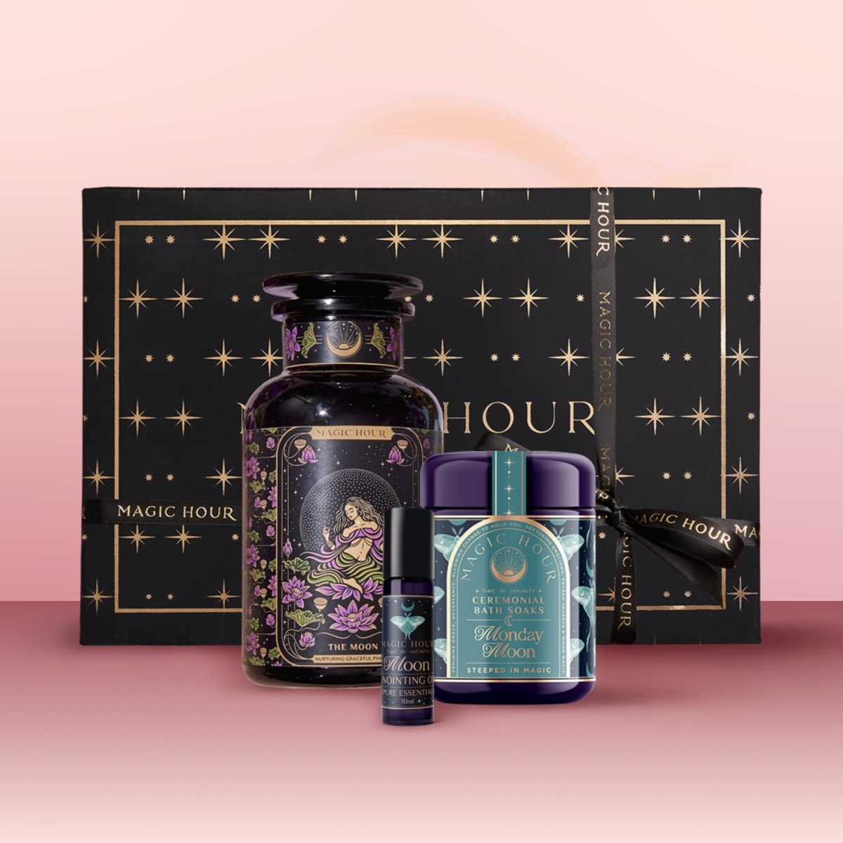 Experience celestial beauty with The Moon Bath & Beauty Box, featuring a luxurious black box with gold stars, a decorative bottle, small roller, and the "Midnight Moon" jar—all presented against a pink backdrop.