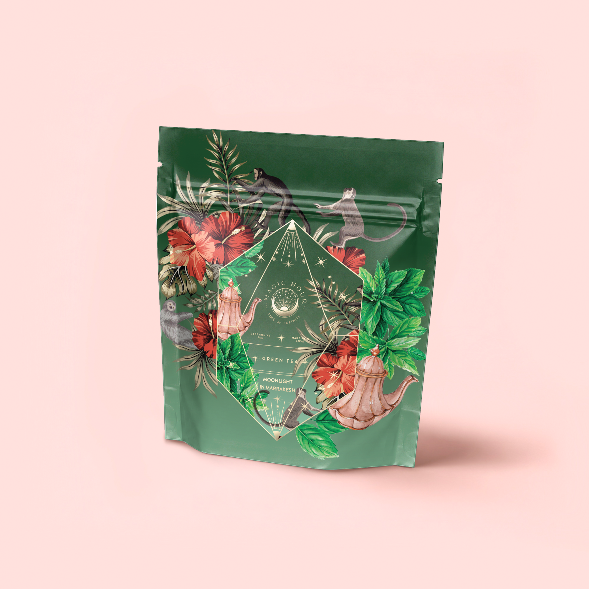 A packaging pouch for Moonlight in Marrakesh: Spiced Mint Green Tea features tropical floral and leaf illustrations, monkeys, and a teapot on a light pink background. The label reads "Moonlight in Marrakesh: Spiced Mint Green Tea.