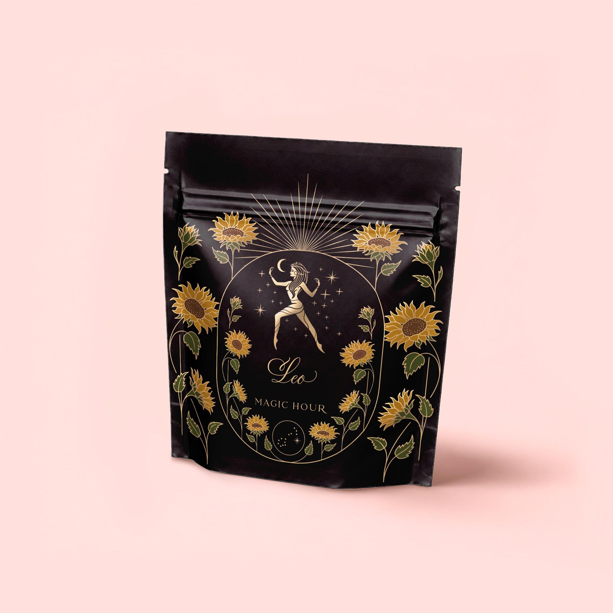 A black resealable bag with gold and yellow floral accents depicts a woman holding a star, labeled "Leo" and "Magic Hour," containing Leo: Queen of Courage Tea of the Sun (Yunnan Black Tea), set against a pink background.
