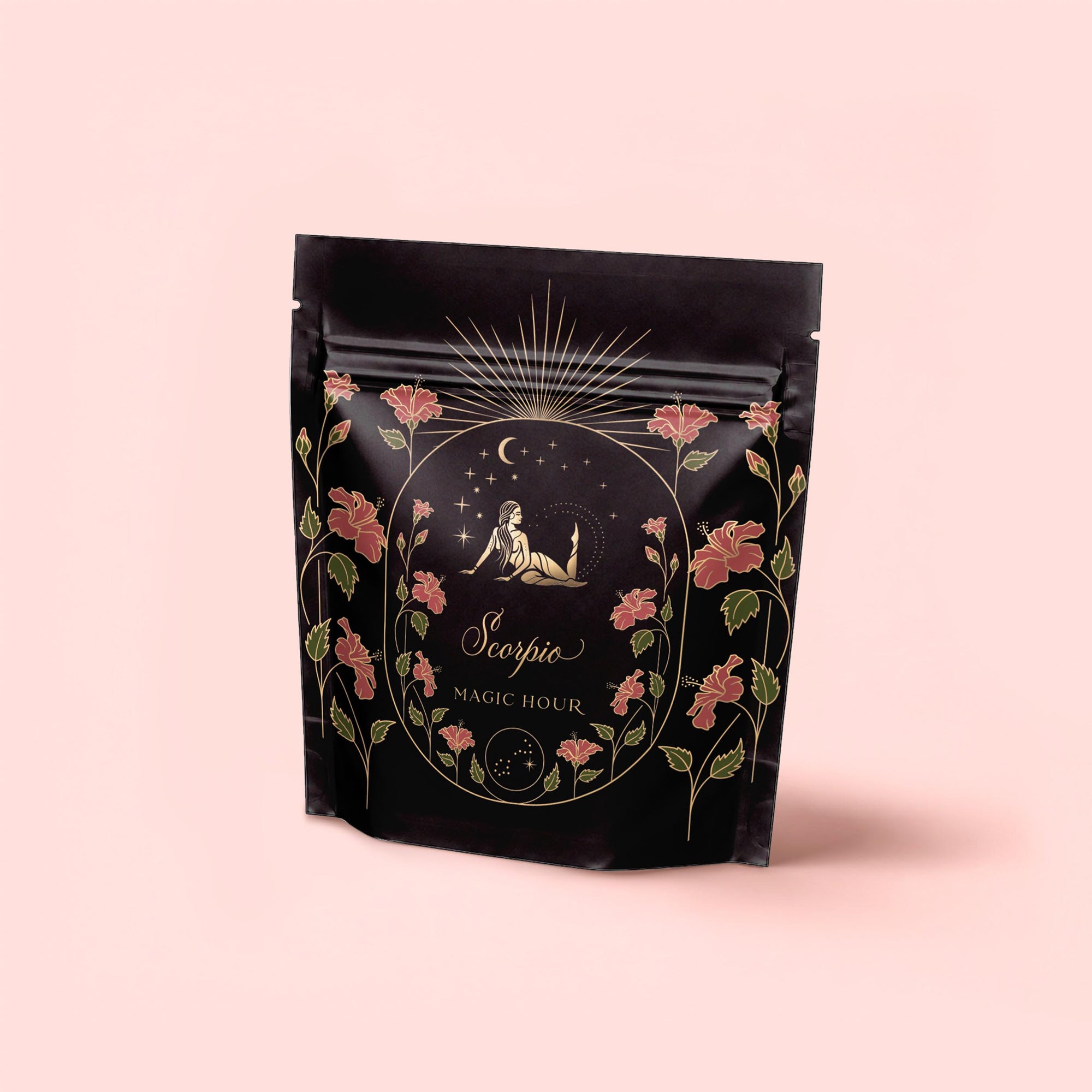 A black resealable pouch with floral designs, gold accents, and an illustration of a woman and scorpion beneath a starry sky features the label “Scorpio Tea for Sensual Brilliance.” Set against pastel pink—perfect for lovers of sensual tea.