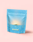 A blue and gold stand-up pouch labeled "Blue Pineapple: Ceremonial Soda Pop Tea" sits against a pink background, adorned with sunburst graphics and bubbles—made with blue spirulina and caffeine-free herbal tea.