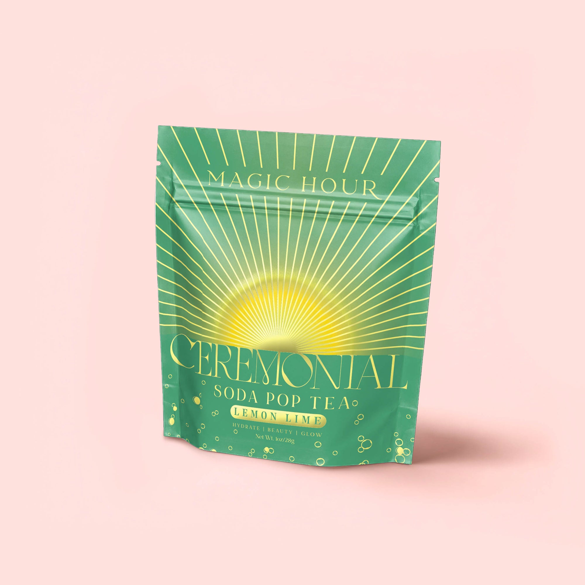 A green and yellow stand-up pouch labeled "Lemon Lime Green Tea: Ceremonial Soda Pop Tea" with a sunburst design, featuring lemon tea and Gymnema Sylvestre, is set against a plain light pink background.
