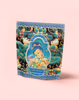 A colorful tea package labeled "Nuwa Goddess of Creation Tea for Intuition: Dragon Yuzu Oolong" features ornate artwork of a serene figure holding tea, surrounded by floral and cloud motifs on a pastel pink background.