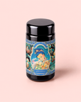 A black jar adorned with a colorful, whimsical label featuring a fairy and flowers, with “Nuwa Goddess of Creation Tea for Intuition: Dragon Yuzu Oolong” in green at the bottom, set against a pale pink background. Inspired by the delicate aroma of Japanese Yuzu essential oil, this enchanting design evokes a sense of magic and tranquility.