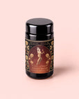 A black tea canister labeled “Monthly Magic Tea Journey Subscription” with an ornate gold and floral design, featuring a central illustration of a woman inspired by goddess archetypes, set against a pale pink background—perfect for those seeking guidance in tea rituals or wishing to explore the magic of a monthly tea subscription.