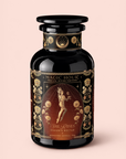 A dark, ornate tea jar labeled “Magic Hour: Teas of the Divine Feminine” features a floating female figure, gold floral designs, and text that reads “Oshun’s Nectar: Honeyed Herbal Tea for Joy & Radiance.”.
