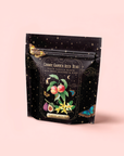 A black resealable bag of Peach Vanilla Black Iced Tea with Figs, blending peach, vanilla, black tea, dried peaches, and figs. The light pink packaging features floral and fruit artwork with a butterfly and starry accents.
