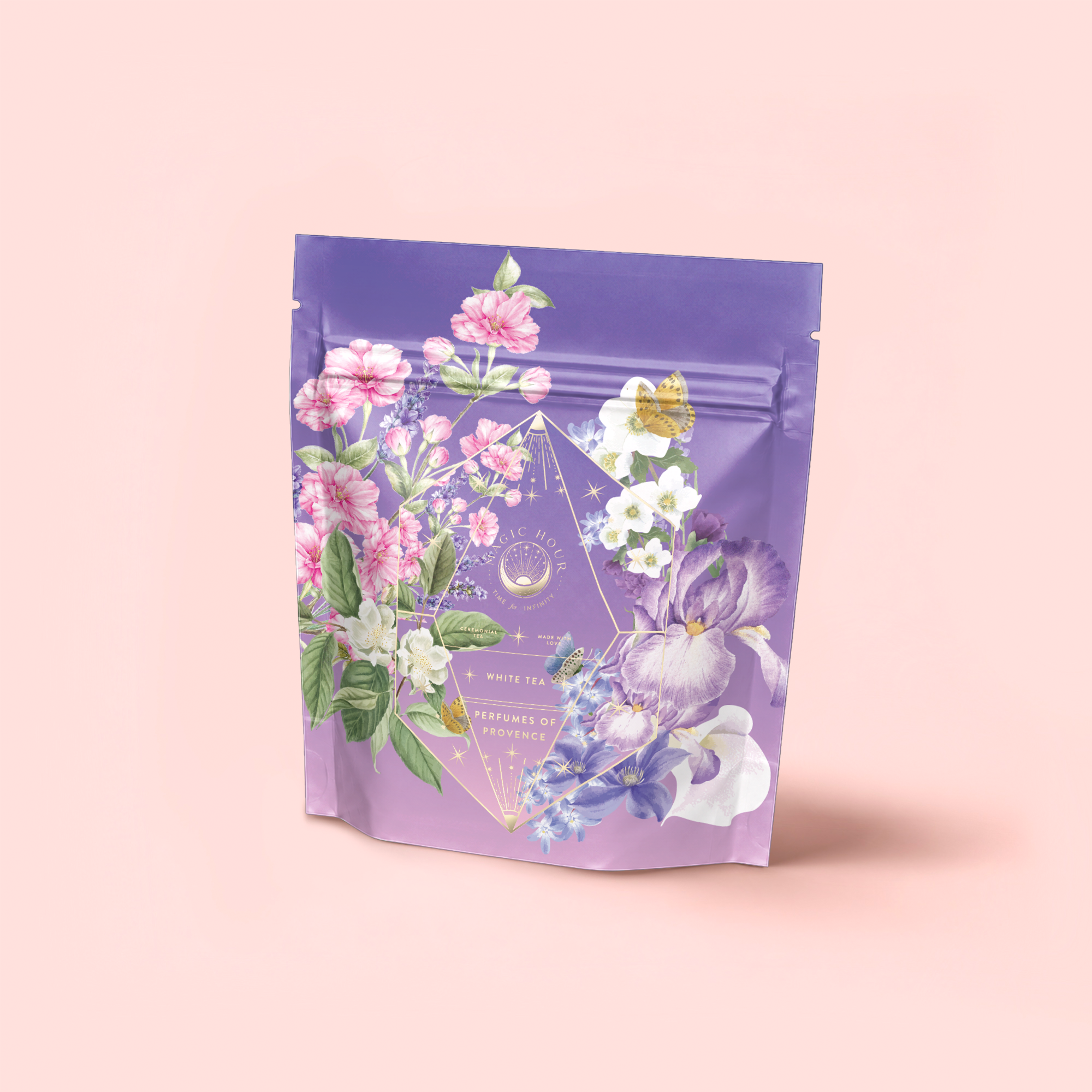 Perfumes of Provence: Lavender Bouquet Tea for Calm Moods and Beautiful Skin comes in a lavender resealable pouch adorned with pink, white, and purple flowers, green leaves, gold geometric accents, and delicate text on a soft pink background.