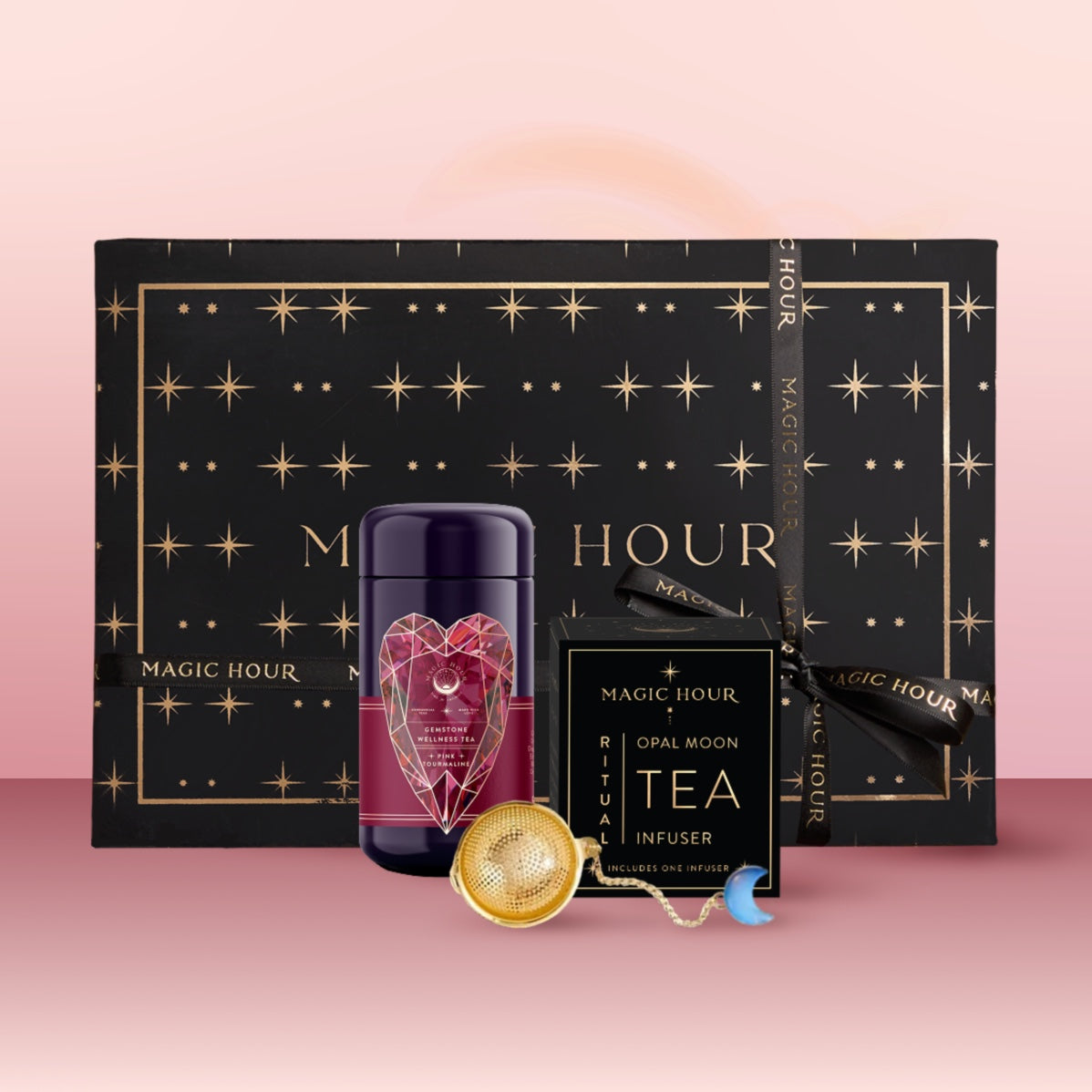 The Pink Tourmaline October Birthstone Mini Gift Set includes a black and gold star box, purple geometric heart tea canister, Opal Moon Tea Infuser, and a gold crescent moon infuser—perfect as an October birthstone or wellness gift set.