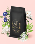 A bag of Pisces: Magnolia-Jasmine Blueberries & Cream Tea with Lion's Mane features a floral Pisces label with a swan, moon, and stars, surrounded by magnolia, Blue Butterfly Pea Flower, and white blossoms on light pink.