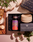 The Pumpkin Lovers Tea & Accessory Gift Set includes a tea canister, a ceramic ceremonial tea bowl, and an "Exquisite Star Sips" package. Alongside it, you'll find a frothy pumpkin spice tea accompanied by cinnamon sticks, cookies, and white flowers beautifully displayed on a wooden board.