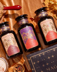 The Pumpkin Spice Essentials Tea Trio Gift Set is elegantly arranged on a satin backdrop. Each apothecary jar features a decorative label adorned with fall-themed graphics. The ensemble is surrounded by autumn leaves, spices, and a steaming cup of tea, creating a cozy seasonal atmosphere.