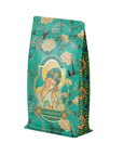 A teal coffee bag, decorated with floral patterns and a serene image of a woman in traditional attire, nods to the ancient art of tea fermentation. Labeled "Compassion: Quan Yin Original Style Oolong," it evokes tranquility through its ornate details and harmonious color scheme.