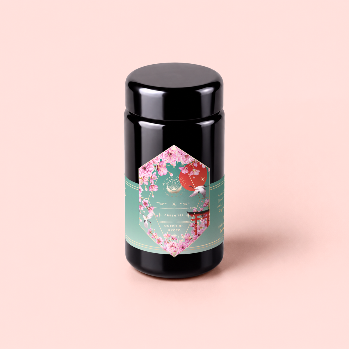 A canister of Queen of Kyoto green tea, featuring a pink floral label with a green band, is displayed against a light pink background. The label highlights its Sencha Green Tea blend, inspired by the lively spirit of the Cherry Blossom Festival.